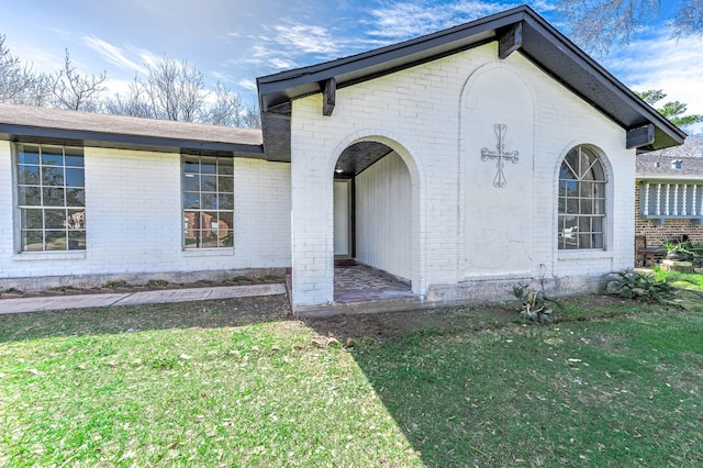 view of property exterior featuring brick siding and a yard