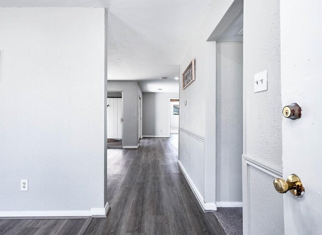 corridor with dark wood-type flooring and baseboards