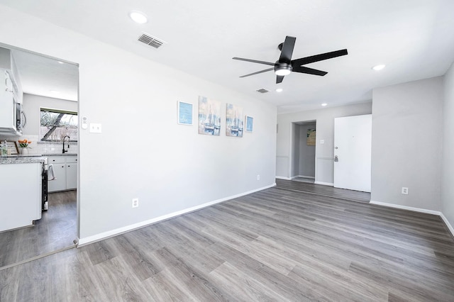 spare room with visible vents, a sink, baseboards, and wood finished floors