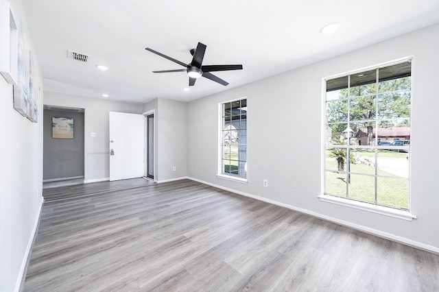 spare room featuring baseboards, visible vents, a wealth of natural light, and wood finished floors