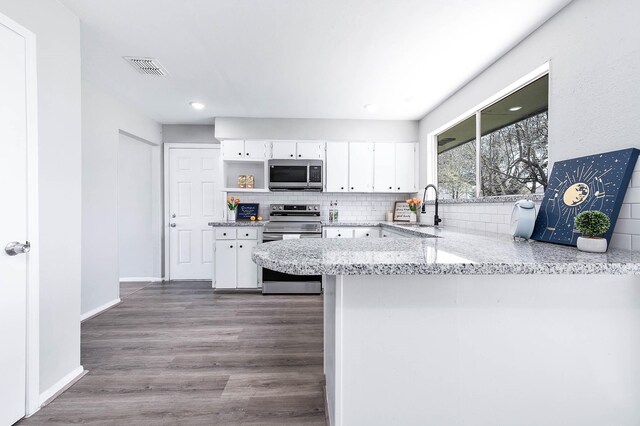 kitchen with white cabinetry, appliances with stainless steel finishes, decorative backsplash, and a sink