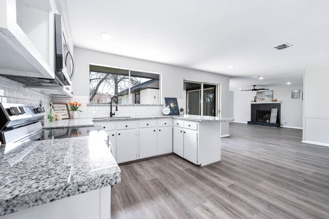 kitchen featuring stainless steel appliances, a fireplace, a sink, visible vents, and backsplash