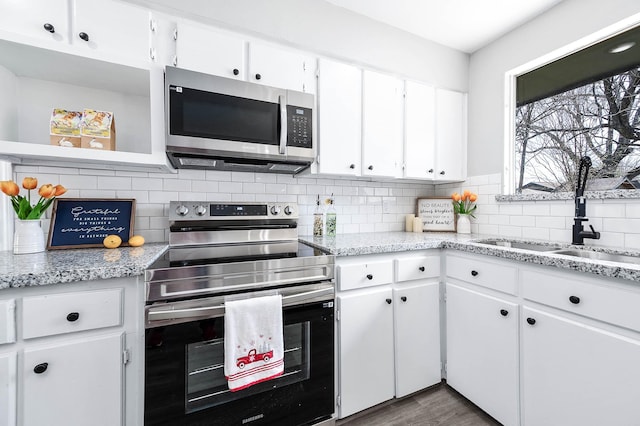 kitchen with tasteful backsplash, appliances with stainless steel finishes, white cabinets, and a sink