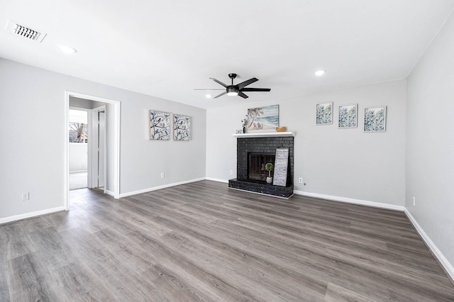 unfurnished living room with baseboards, visible vents, a ceiling fan, wood finished floors, and a fireplace