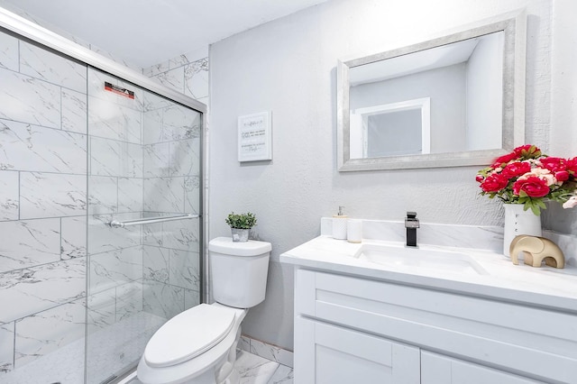 bathroom featuring marble finish floor, vanity, a marble finish shower, and toilet