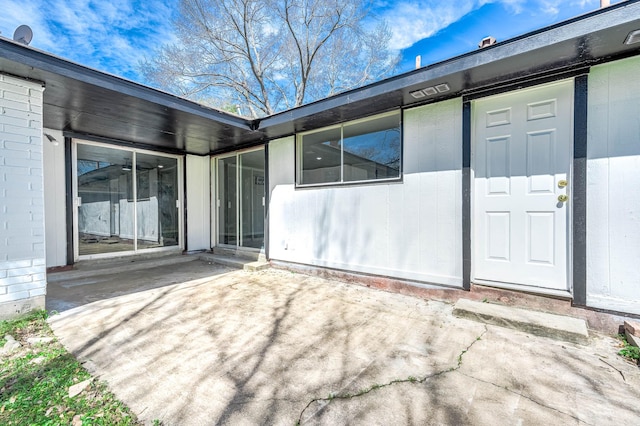 exterior space with brick siding and a patio