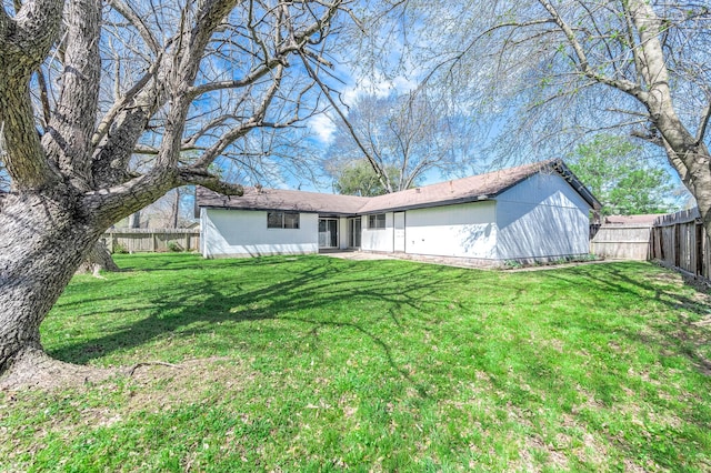 rear view of house featuring a fenced backyard and a lawn