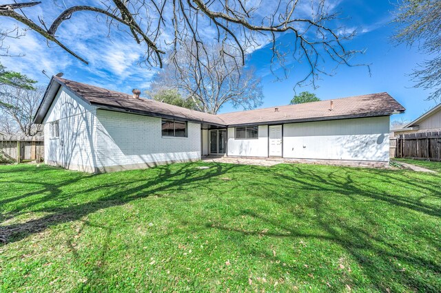 back of house with a yard, brick siding, and fence