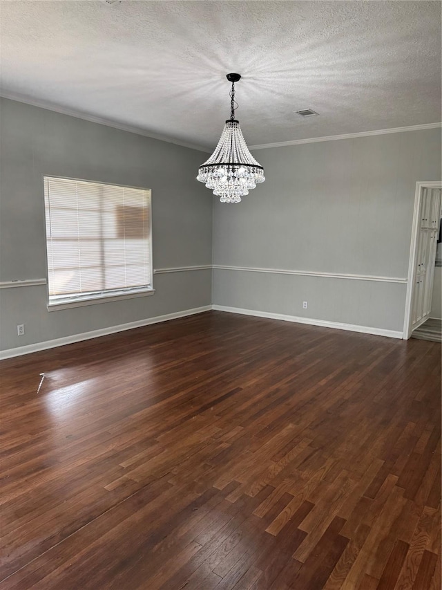 empty room with visible vents, ornamental molding, dark wood-style flooring, a textured ceiling, and a notable chandelier