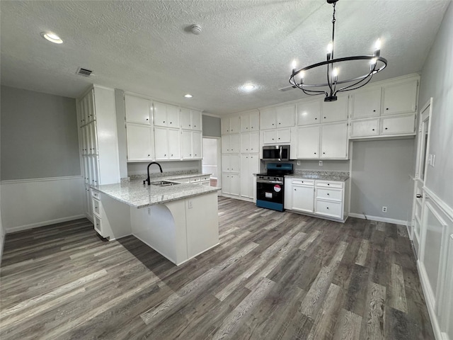 kitchen featuring a peninsula, dark wood-style flooring, a sink, white cabinets, and appliances with stainless steel finishes