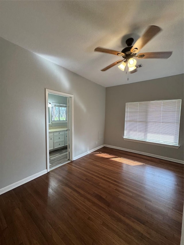 spare room featuring a ceiling fan, visible vents, baseboards, and wood finished floors