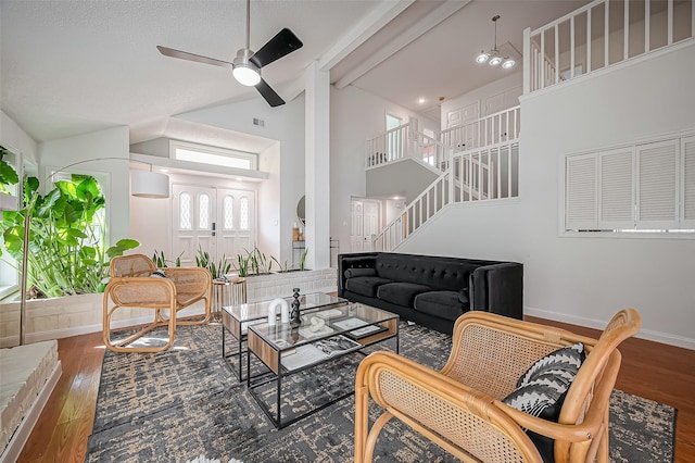 living room with stairs, high vaulted ceiling, wood finished floors, and baseboards