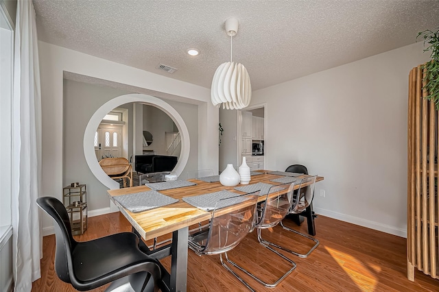 office space with visible vents, a textured ceiling, baseboards, and wood finished floors