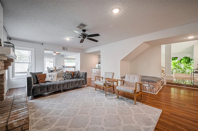 living room featuring baseboards, a textured ceiling, visible vents, and wood finished floors