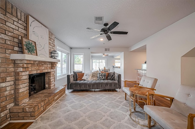 living area featuring a textured ceiling, a fireplace, wood finished floors, and visible vents