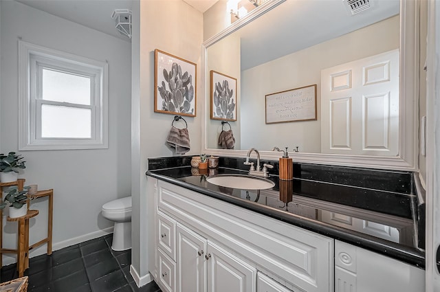 bathroom featuring visible vents, toilet, vanity, baseboards, and tile patterned floors