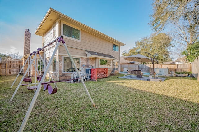 back of property featuring a yard, a fenced backyard, a patio, and a playground