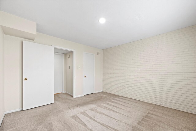 empty room with brick wall, baseboards, and carpet flooring