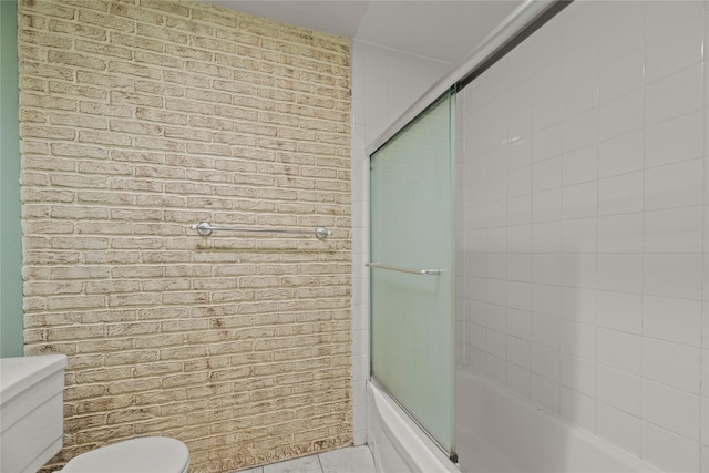 full bathroom with toilet, shower / bath combination with glass door, brick wall, and tile patterned flooring