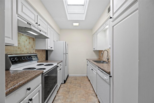 kitchen with white appliances, a skylight, white cabinets, under cabinet range hood, and a sink