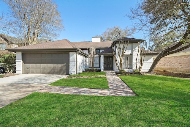 view of front facade featuring brick siding, a front lawn, a chimney, driveway, and an attached garage