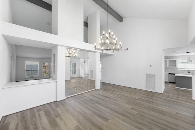 interior space featuring wood finished floors, visible vents, an inviting chandelier, a sink, and beamed ceiling