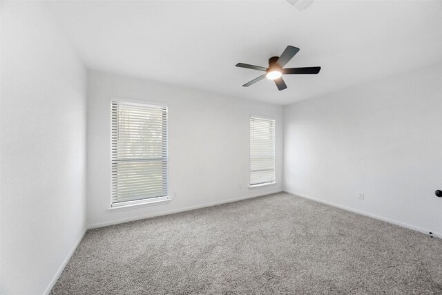 carpeted spare room with a healthy amount of sunlight, baseboards, and ceiling fan