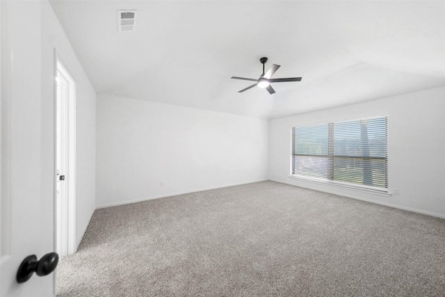 empty room featuring visible vents, carpet flooring, a ceiling fan, and vaulted ceiling