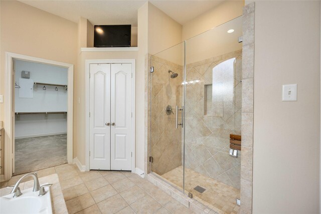 bathroom with tile patterned flooring, a bath, baseboards, and a stall shower