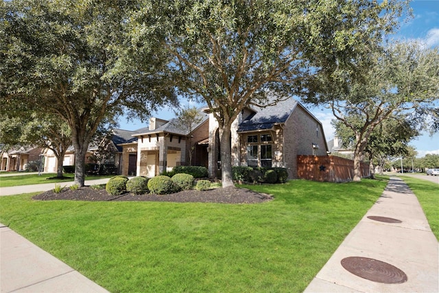 view of front facade with stone siding, a front lawn, and fence