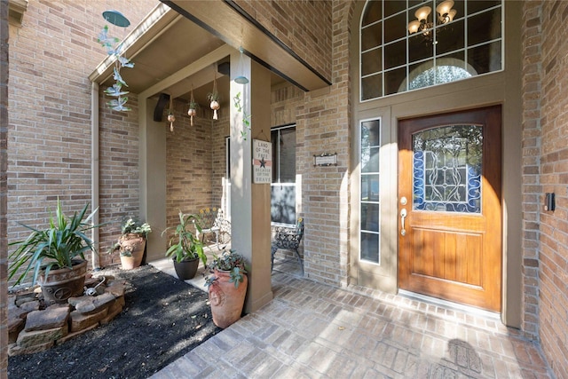 entrance to property with covered porch and brick siding