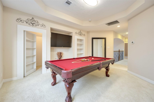 recreation room featuring light carpet, visible vents, a raised ceiling, and built in features