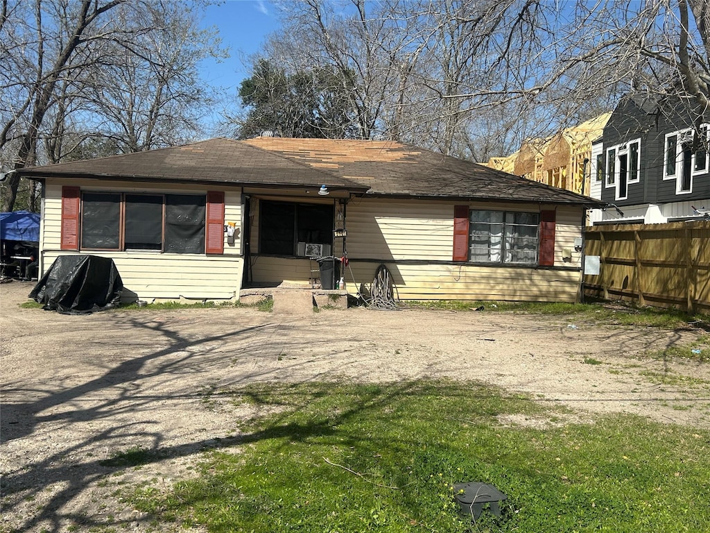 view of front of house featuring dirt driveway, a front lawn, and fence