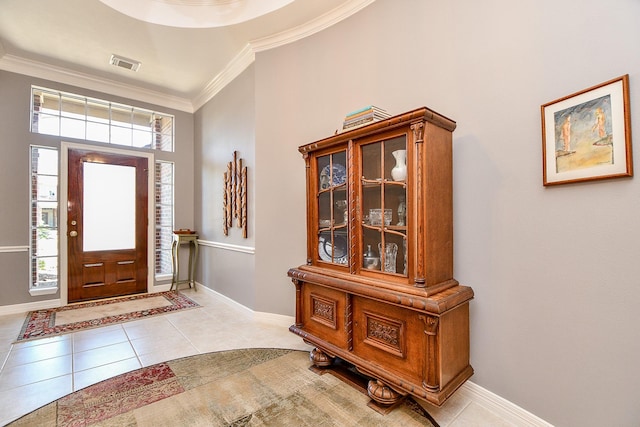 foyer entrance with light tile patterned flooring, visible vents, crown molding, and baseboards