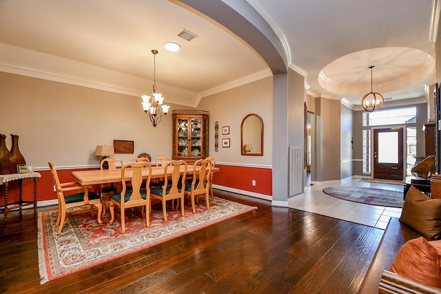 dining space with a chandelier, visible vents, arched walkways, and hardwood / wood-style floors