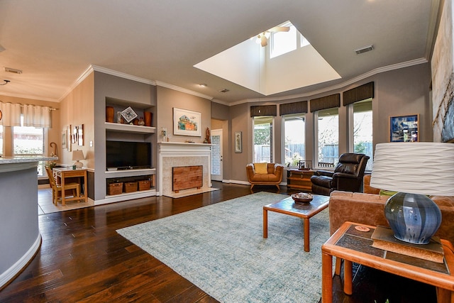 living area with a wealth of natural light, visible vents, a fireplace with flush hearth, and hardwood / wood-style floors