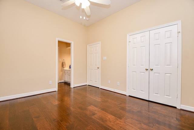 unfurnished bedroom featuring ceiling fan, baseboards, a closet, ensuite bathroom, and dark wood-style floors