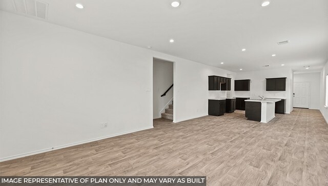 unfurnished living room with light wood-style flooring, recessed lighting, visible vents, baseboards, and stairway