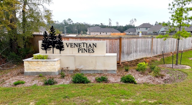 community / neighborhood sign with fence and a lawn