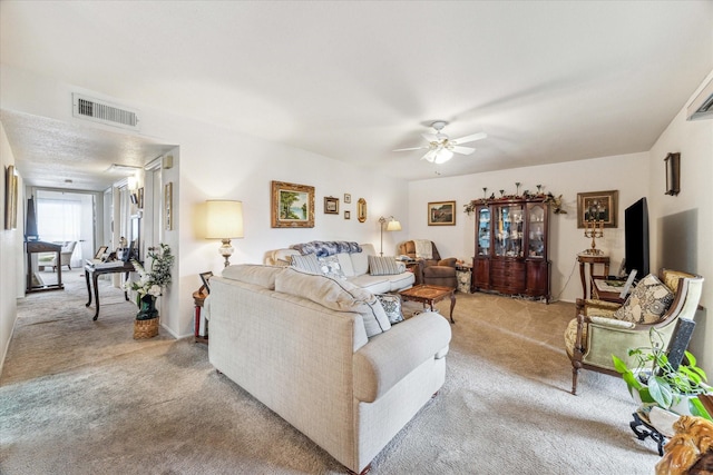 living room featuring a ceiling fan, visible vents, and light carpet