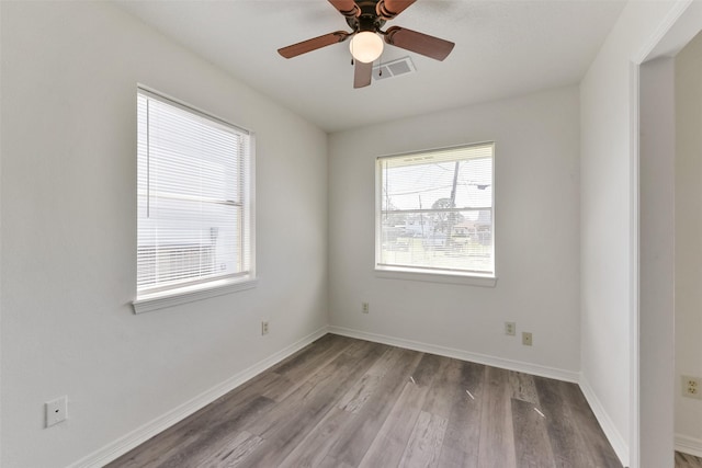 unfurnished room with ceiling fan, wood finished floors, visible vents, and baseboards