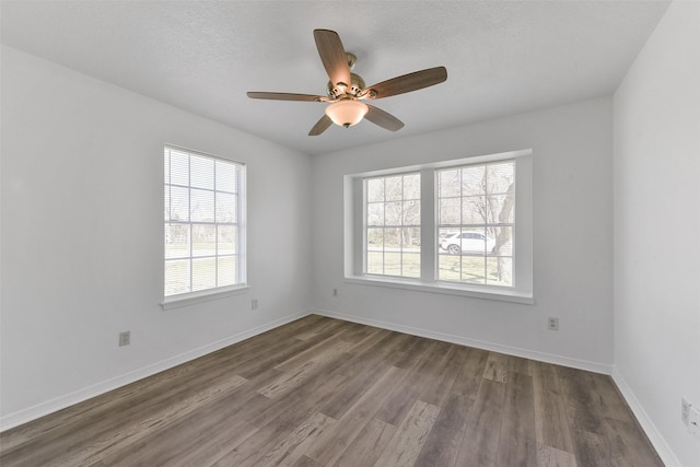 empty room featuring ceiling fan, a textured ceiling, baseboards, and wood finished floors