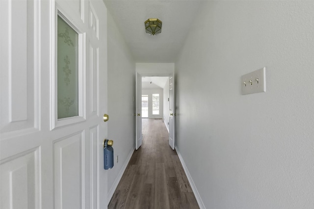 corridor with dark wood-style flooring and baseboards