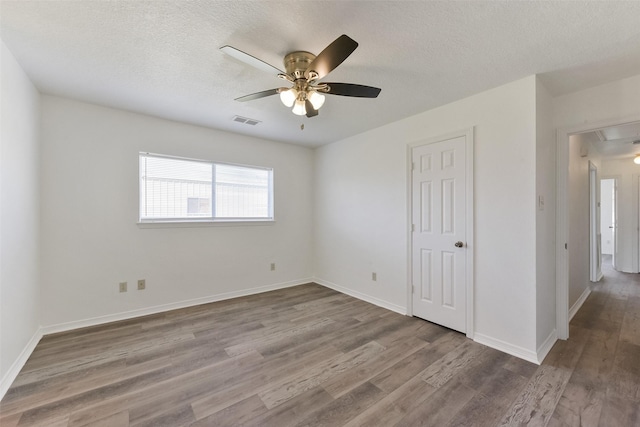 spare room with attic access, visible vents, a textured ceiling, and wood finished floors