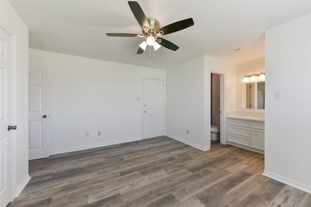 unfurnished bedroom with ceiling fan, baseboards, wood finished floors, and ensuite bathroom