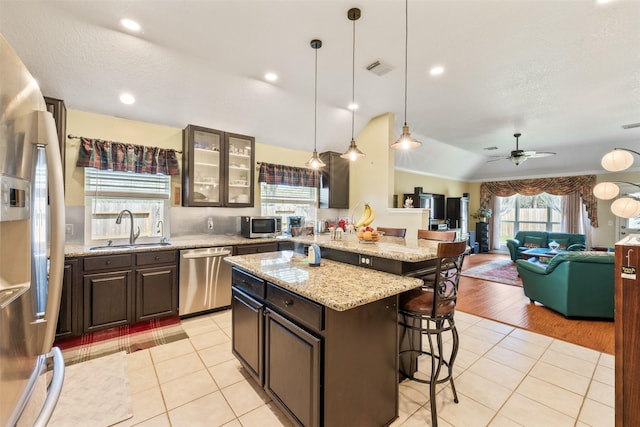 kitchen with appliances with stainless steel finishes, a kitchen breakfast bar, a sink, and light tile patterned flooring