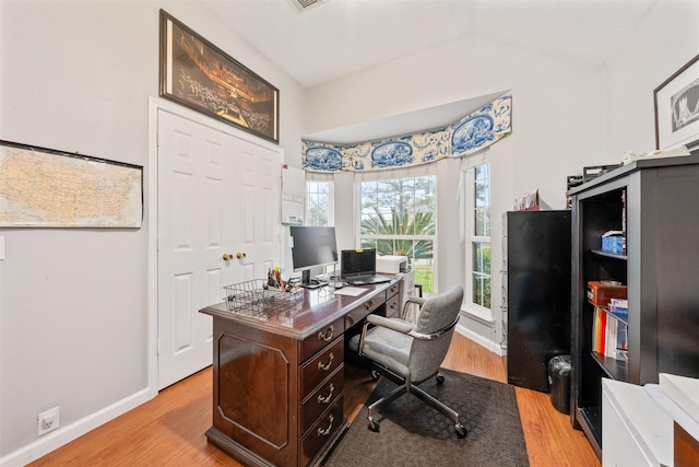 office space with vaulted ceiling, light wood-style flooring, and baseboards