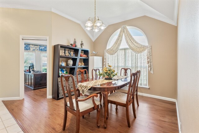 dining room with vaulted ceiling, crown molding, light wood-style flooring, and an inviting chandelier