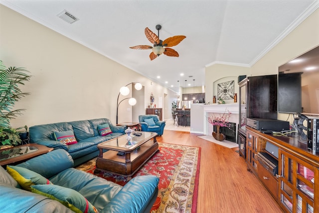 living room with visible vents, ornamental molding, a high end fireplace, ceiling fan, and wood finished floors