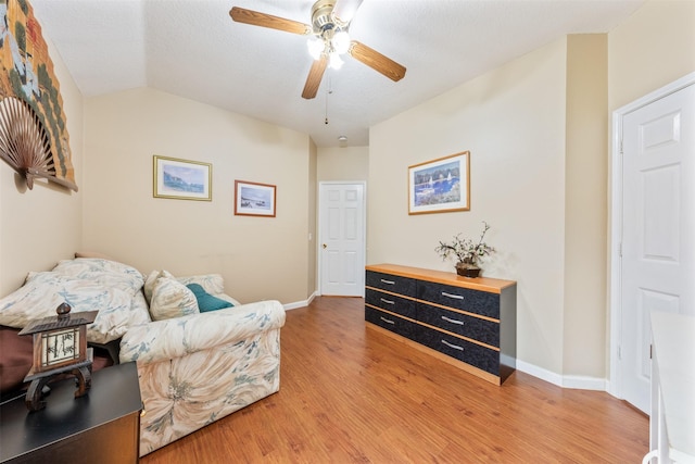 sitting room featuring lofted ceiling, light wood-style floors, baseboards, and a ceiling fan